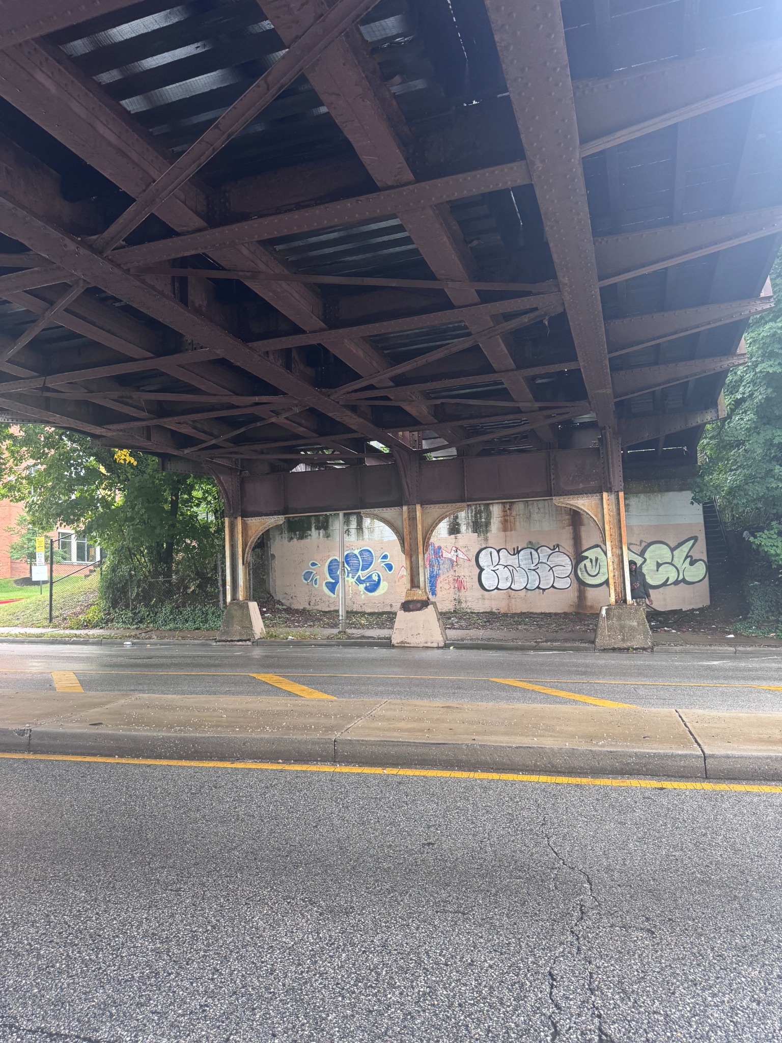 Steel bridge above a wet street and painted wall