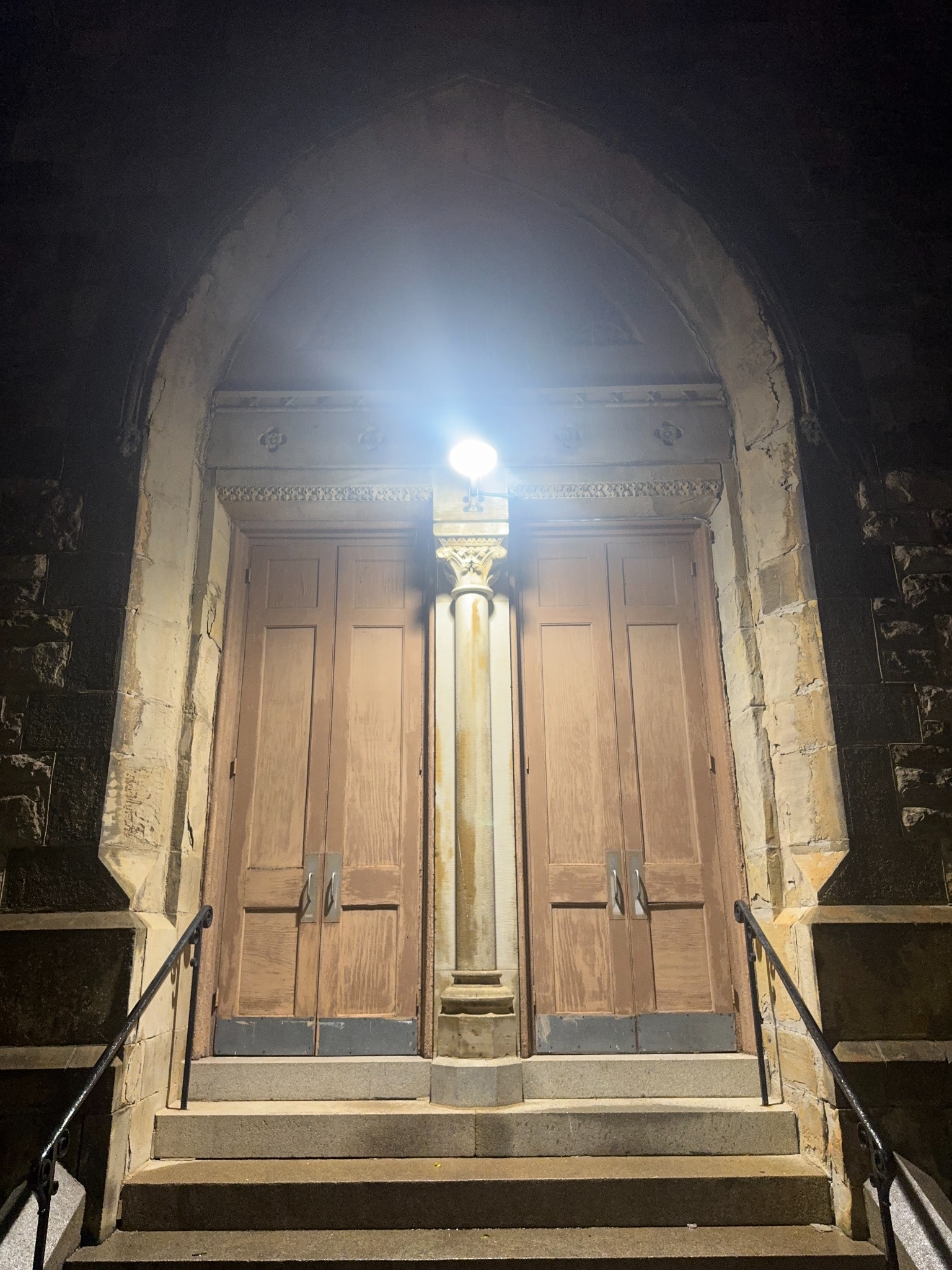 Illuminated church doors above stone steps in Harlem Park